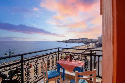 a table on a balcony with a view of the ocean at Scorpios Family Rooms in Palaiochóra