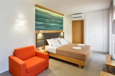 a bedroom with a bed and a orange chair at Elia Kalamaki Hotel in Kalamaki Chanion