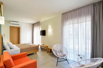 a bedroom with a bed and a couch and chairs at Elia Kalamaki Hotel in Kalamaki Chanion