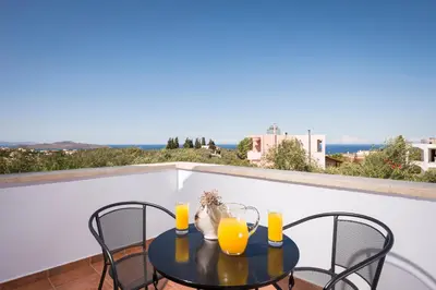a table with two glasses of orange juice on a balcony at Orionas Village in Kato Daratso