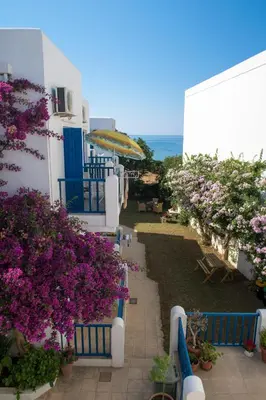 a balcony of a building with flowers and an umbrella at Astra Hotel Apartments in Kato Daratso