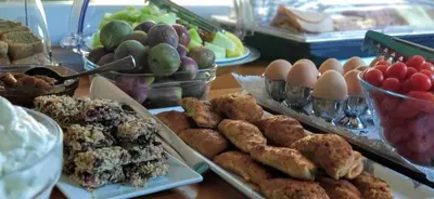a table with plates of pastries and eggs and fruit at Hotel Peli in Kissamos