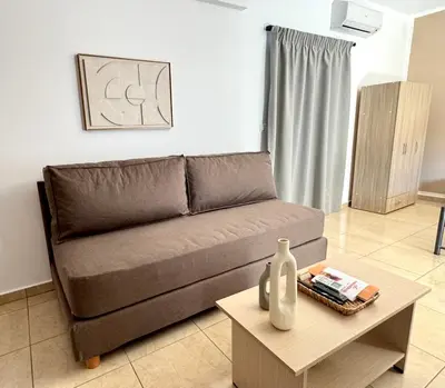 a living room with a brown couch and a table at Pachia Ammos Falasarna in Falasarna