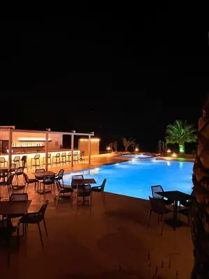 a swimming pool with tables and chairs at night at Pachia Ammos Falasarna in Falasarna