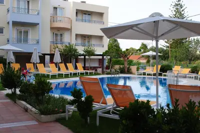a swimming pool with chairs and an umbrella next to a hotel at Melina Beach in Plataniás