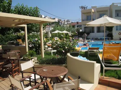 a patio with tables and chairs and a swimming pool at Melina Beach in Plataniás