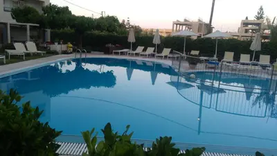 a large blue swimming pool with chairs and umbrellas at Melina Beach in Plataniás
