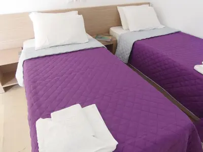 two beds in a room with purple sheets at Angelica Studios and Apartments in Agia Marina Nea Kydonias