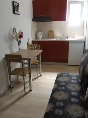 a kitchen with a table and chairs and a table and a sink at Angelica Studios and Apartments in Agia Marina Nea Kydonias