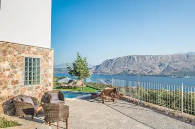 a stone house with a view of the water at Istros Villas - with Pools, BBQ & Heated Spa Whirlpools, By ThinkVilla in Korakiaí