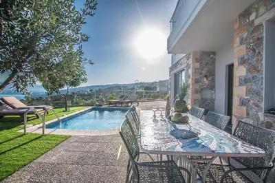 a patio with a table and chairs next to a pool at Istros Villas - with Pools, BBQ & Heated Spa Whirlpools, By ThinkVilla in Korakiaí