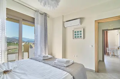 a white bedroom with a bed and a balcony at Lydia's Apartments in Kissamos