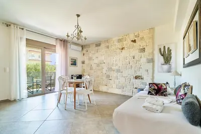 a room with two beds and a table and a brick wall at Lydia's Apartments in Kissamos