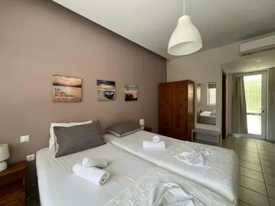 a bedroom with a large white bed with towels on it at Artemis Rooms two steps by the sea in Plataniás