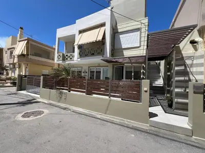 a house with a wooden fence in front of a street at Artemis Rooms two steps by the sea in Plataniás