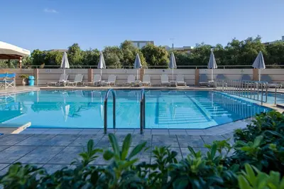 a large swimming pool with chairs and umbrellas at Dias Hotel Apartments in Agia Marina Nea Kydonias