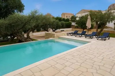 a swimming pool with chairs and a umbrella and trees at Villa Antonousa - Private Pool Oasis in Kerá