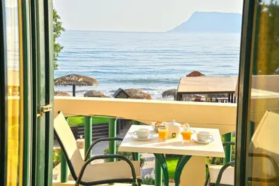 a table and chairs on a balcony with a view of the ocean at Maria Beach Hotel in Kissamos