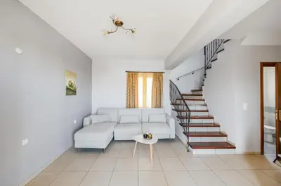 a living room with a white couch and stairs at Orion Star in Agia Marina Nea Kydonias