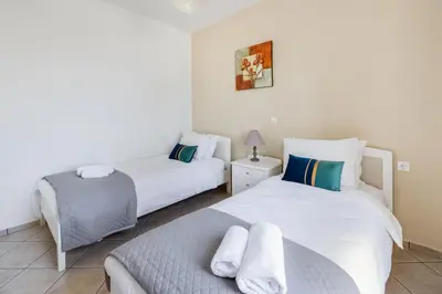 a bedroom with two beds and a chair at Orion Star in Agia Marina Nea Kydonias