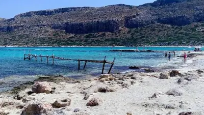 a beach with a wooden bridge in the water at Sun Nicolas in Kato Daratso