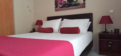 a bedroom with a pink and white bed with two red pillows at Modern Apartment Chania Center in Chania Town