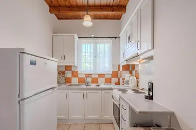 a kitchen with white cabinets and a white refrigerator at Helianthos Villas in Douliana
