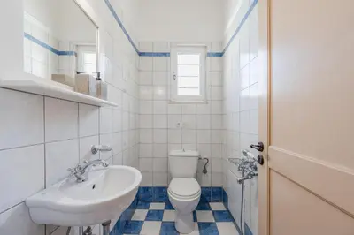 a white bathroom with a toilet and a sink at Helianthos Villas in Douliana