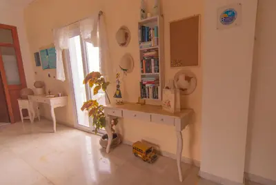 a room with a desk with a book shelf and a window at Oriental Bay in Palaiochóra