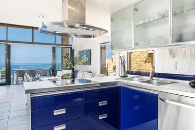 a kitchen with blue cabinets and a view of the ocean at Villa Emilia front sea in Kalathas