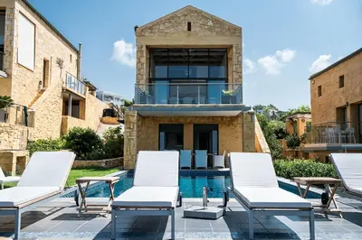 a group of white lounge chairs next to a swimming pool at Villa Emilia front sea in Kalathas
