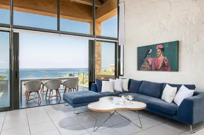 a living room with a blue couch and a table at Villa Emilia front sea in Kalathas