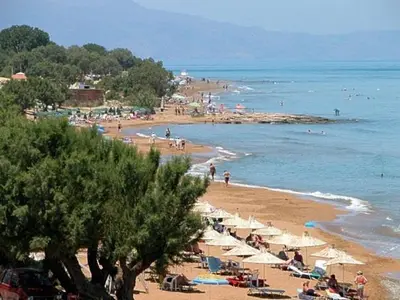 a beach with a bunch of people and umbrellas at Kato Stalos Beach in Stalos