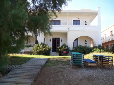 a house with chairs and a wooden walkway in front of it at Kato Stalos Beach in Stalos