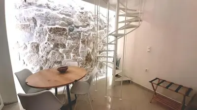a table and chairs in a room with a stone wall at Apartment Split Level in Chania Town