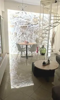 a dining room with a table and chairs and a stone wall at Apartment Split Level in Chania Town