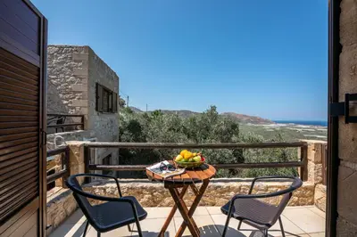 a table with a bowl of fruit on a balcony at The Stonemade Houses in Falasarna
