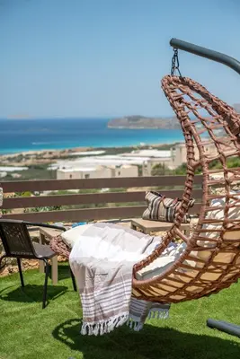 a rattan chair with a table and the ocean in the background at The Stonemade Houses in Falasarna