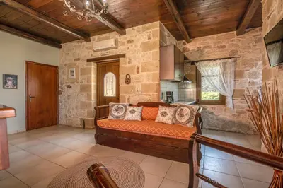 a living room with a couch in a stone wall at The Stonemade Houses in Falasarna