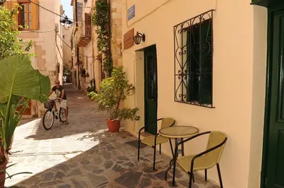 a person riding a bike down a street with a table and chairs at Eleonora in Chania Town