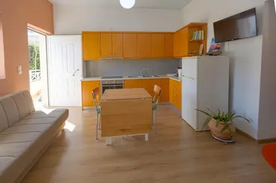a kitchen with yellow cabinets and a table and a couch at In And Out in Chania Town