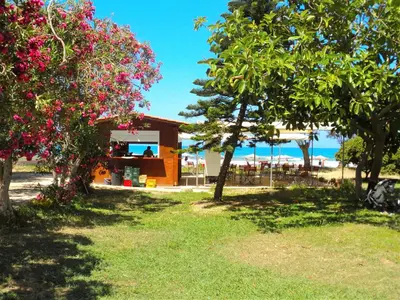 a restaurant with trees and flowers on the beach at Thodorou Villa in Agia Marina Nea Kydonias