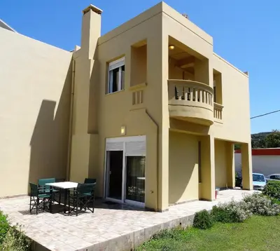 a house with a balcony and a table at Platanias House on the Beach in Plataniás