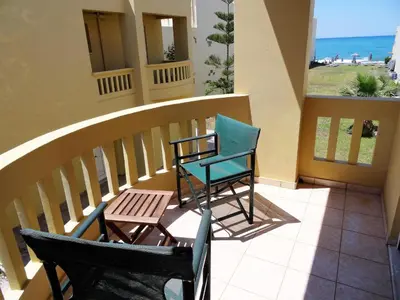 two chairs and a table on a balcony with the ocean at Platanias House on the Beach in Plataniás