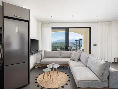 a living room with a couch and a large window at Luxury Apartment with private pool in Tavronitis
