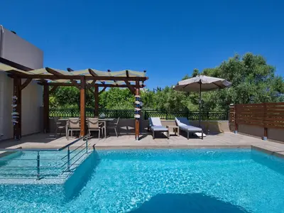a swimming pool with a table and chairs and an umbrella at Villa Andreas in Kamisianá