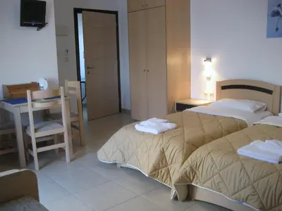 a hotel room with two beds and a table and chair at Yiorgos Studios in Palaiochóra