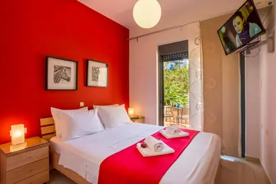 a red bedroom with a bed with two towels on it at Caravella Luxury Apartments in Palaiochóra