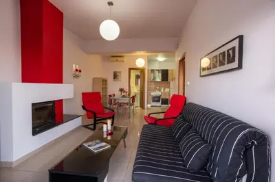 a living room with a black couch and red chairs at Caravella Luxury Apartments in Palaiochóra