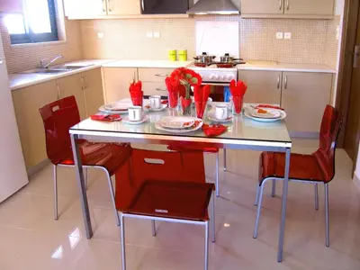 a kitchen with a table with red chairs at Caravella Luxury Apartments in Palaiochóra